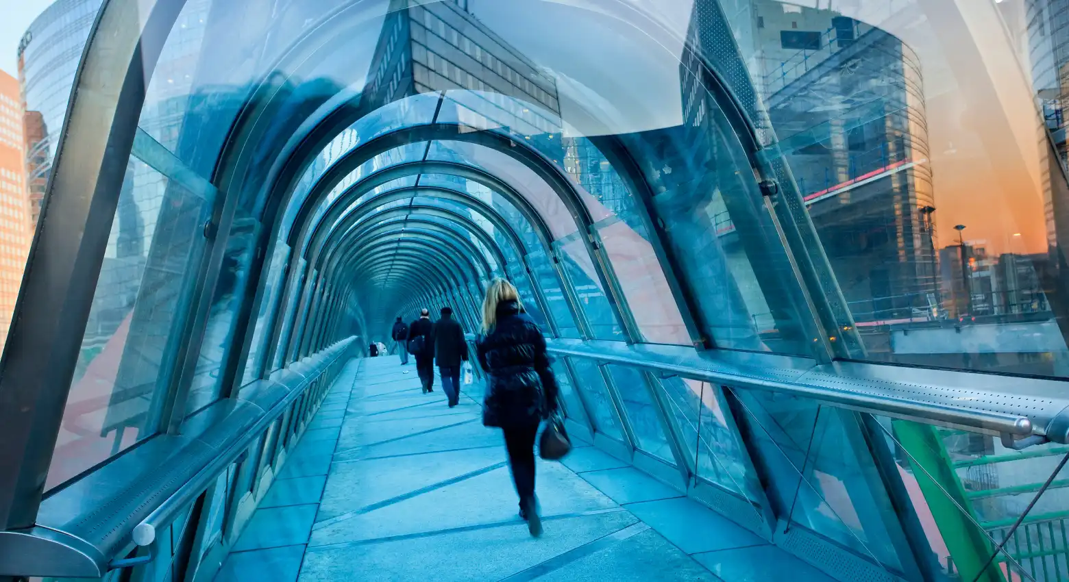 Pessoas caminhando em uma ponte entre edifícios de arquitetura moderna 
