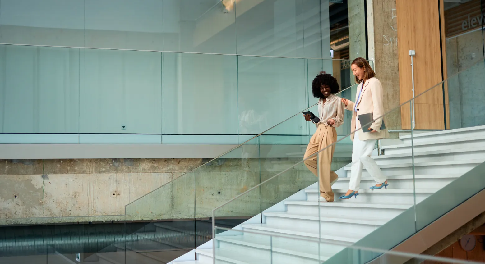 Duas mulheres caminhando e conversando em um prédio moderno 