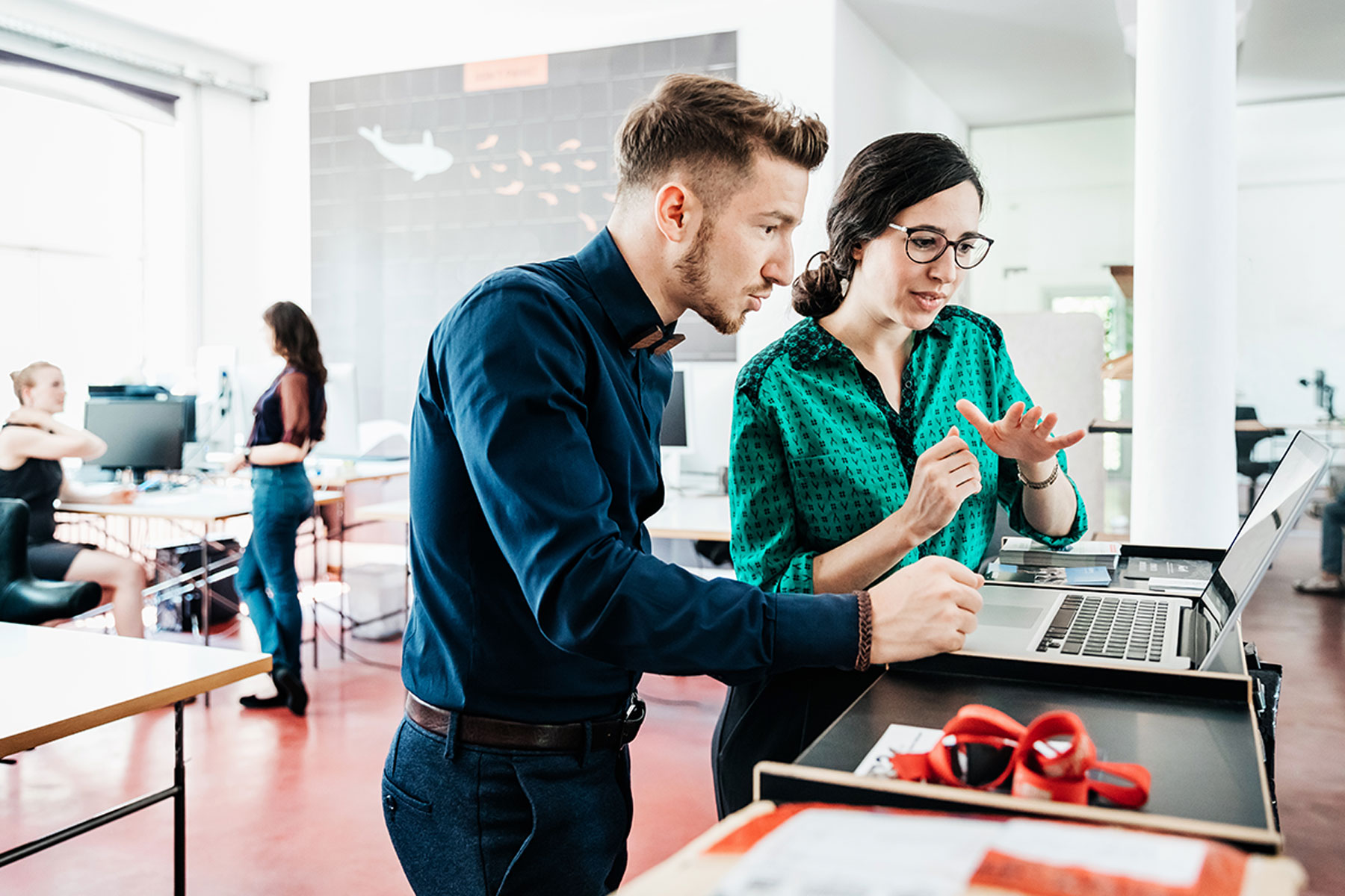 Uma funcionária e um funcionário falam sobre privacidade enquanto olham para um laptop.